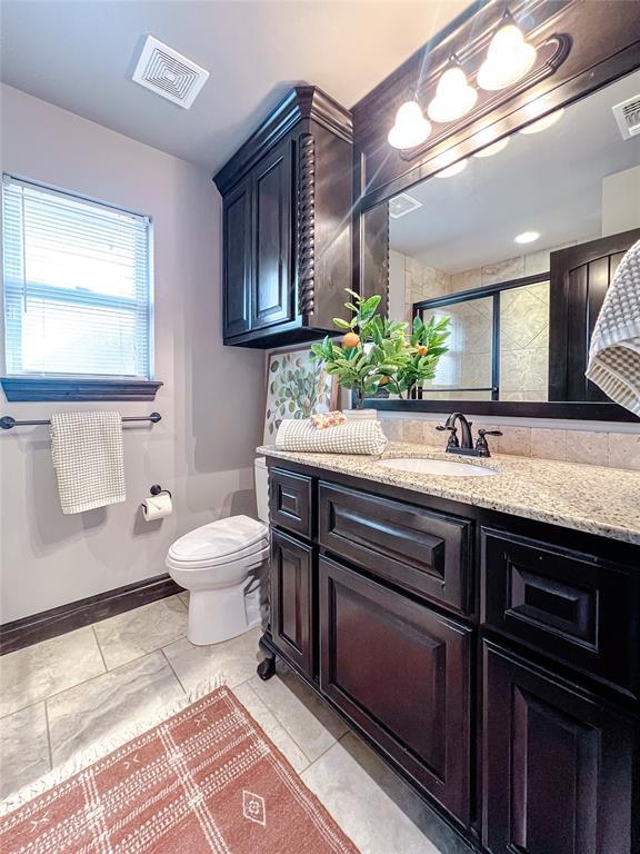 bathroom with decorative backsplash, vanity, toilet, and a shower with door