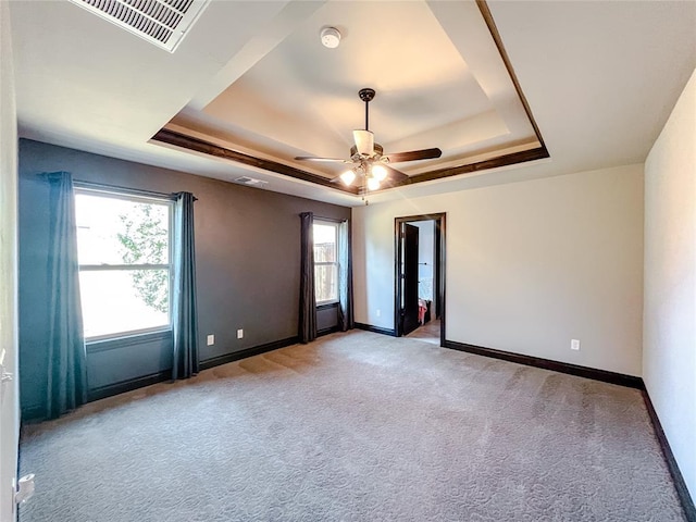 unfurnished room featuring light carpet, a tray ceiling, ceiling fan, and a healthy amount of sunlight