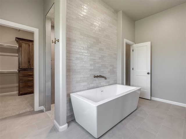 full bathroom with a freestanding tub, tile walls, baseboards, and tile patterned floors