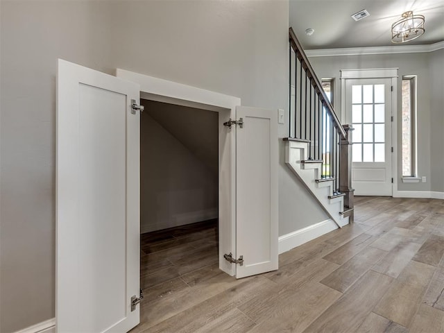 interior space with baseboards, wood finished floors, visible vents, and crown molding