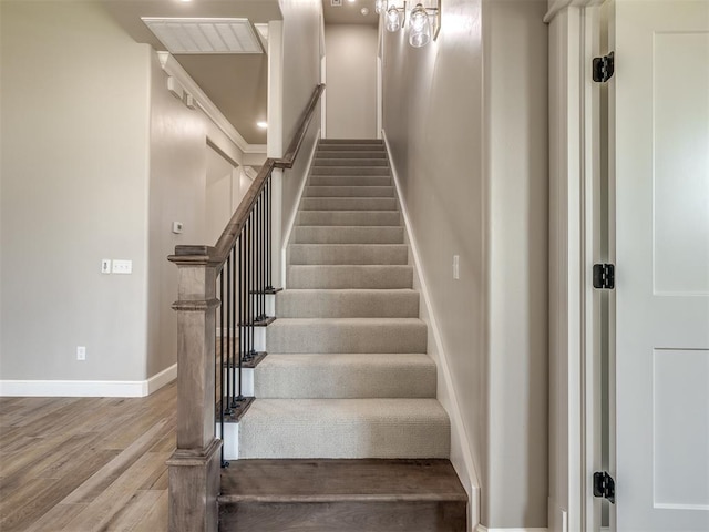 stairway with visible vents, baseboards, and wood finished floors