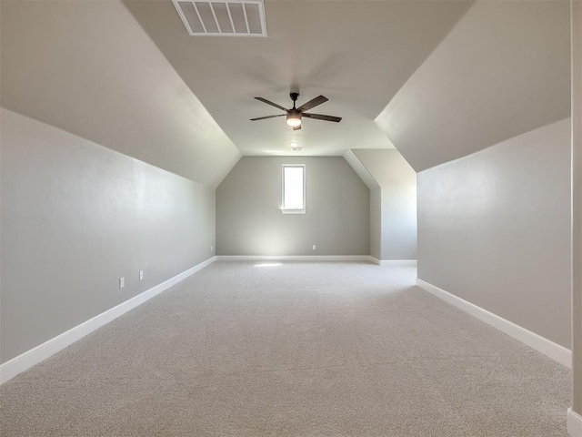 additional living space featuring visible vents, baseboards, light colored carpet, lofted ceiling, and ceiling fan