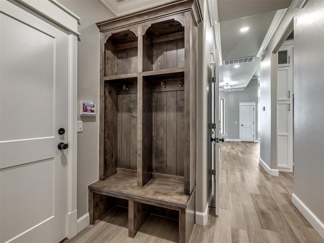 mudroom featuring crown molding, baseboards, and light wood-style floors