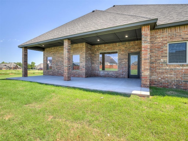 rear view of house with a yard, a patio, and brick siding