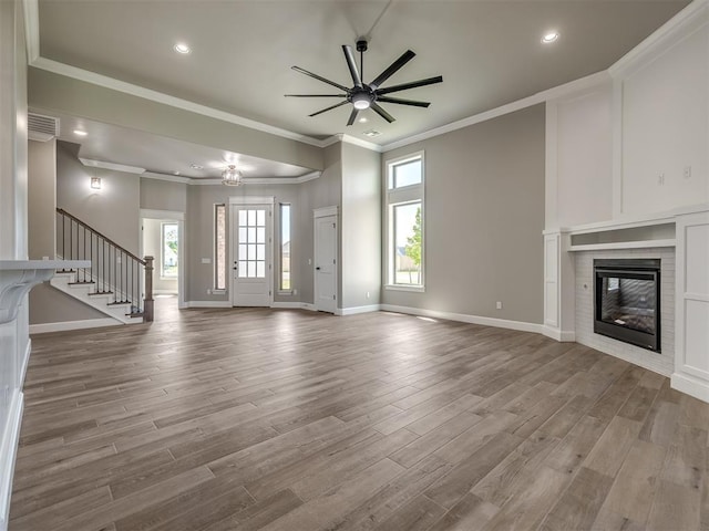 unfurnished living room featuring a ceiling fan, a glass covered fireplace, wood finished floors, baseboards, and stairs