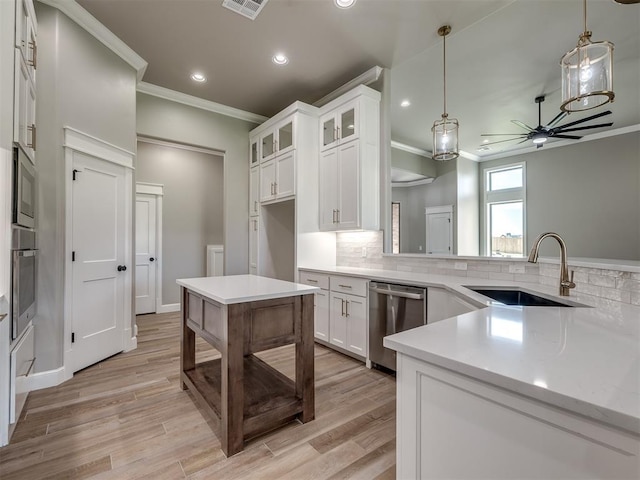 kitchen featuring ceiling fan, stainless steel appliances, a sink, decorative backsplash, and light wood finished floors