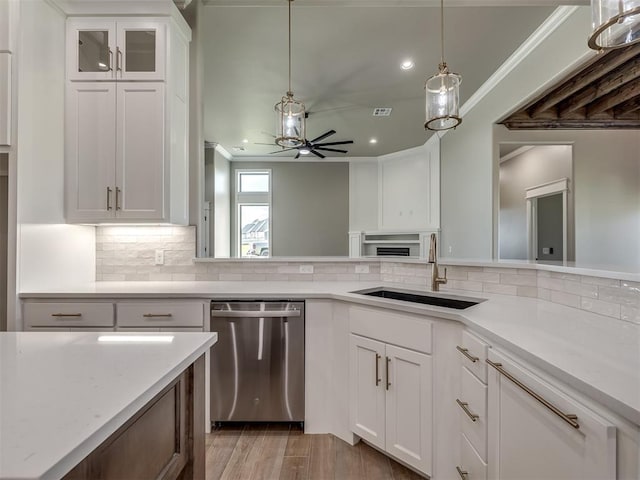 kitchen with a sink, white cabinetry, a ceiling fan, stainless steel dishwasher, and crown molding