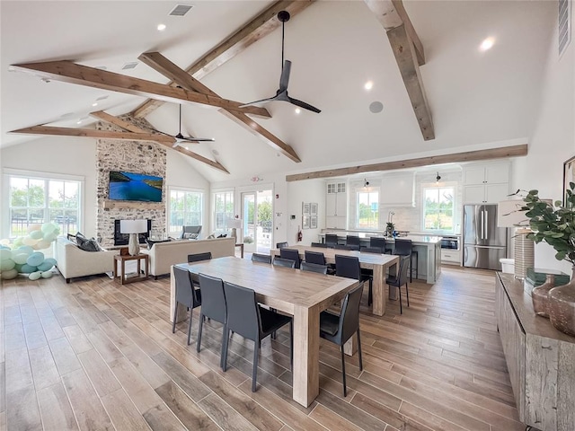 dining area with high vaulted ceiling, beam ceiling, light wood-style floors, and a ceiling fan