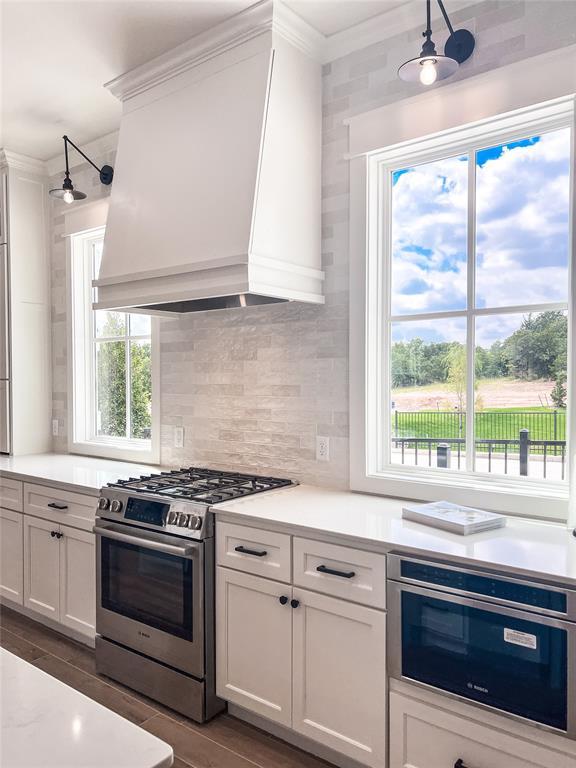 kitchen with ceiling fan, light countertops, custom range hood, ornamental molding, and stainless steel gas stove