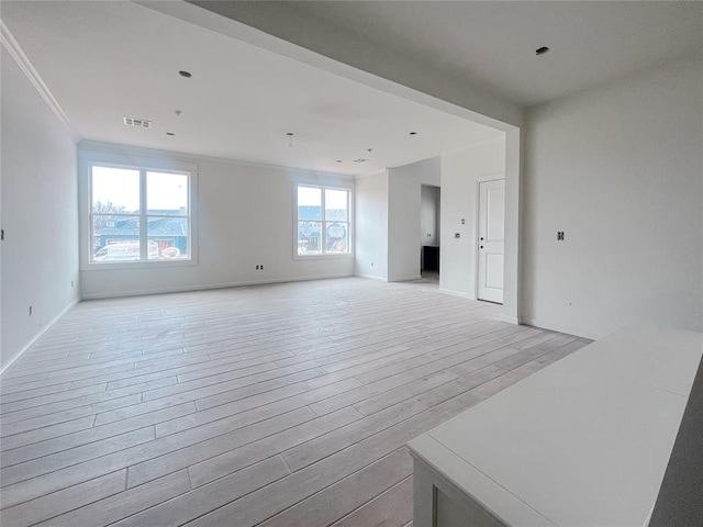 unfurnished room with visible vents, baseboards, crown molding, and light wood-style floors