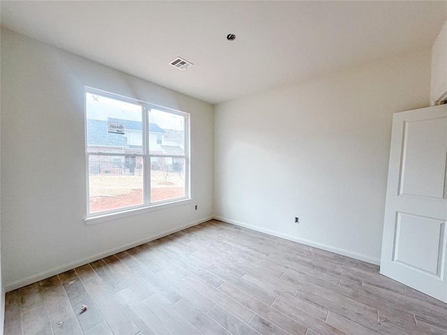 spare room featuring light wood-style flooring, baseboards, and visible vents