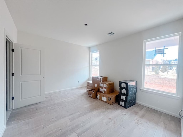 empty room with visible vents, light wood-type flooring, and baseboards