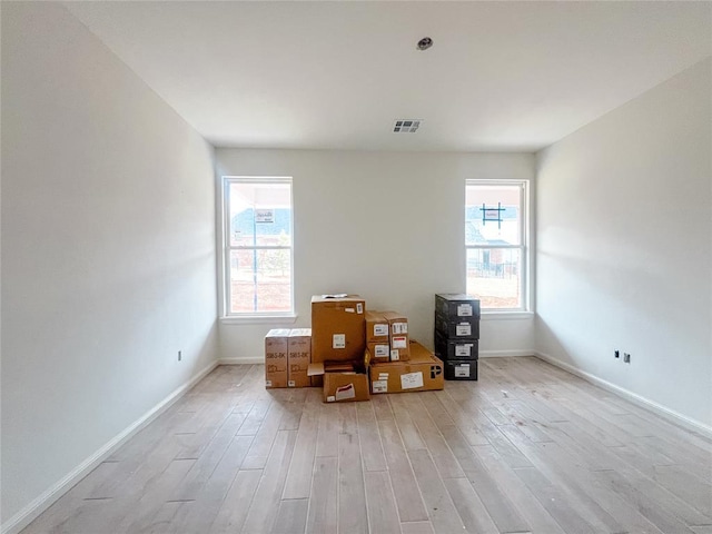 unfurnished room featuring light wood-style flooring, baseboards, and visible vents