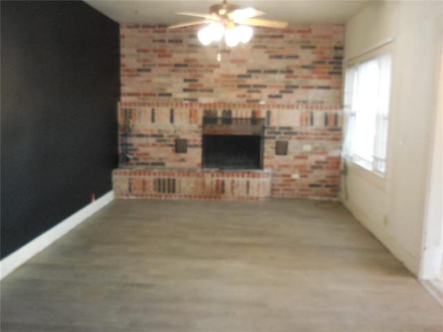 unfurnished living room featuring a brick fireplace and ceiling fan