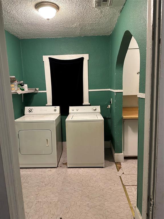 clothes washing area featuring washer and dryer and a textured ceiling