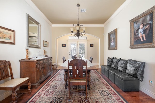 dining space featuring a notable chandelier, ornamental molding, and dark wood-type flooring