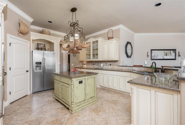 kitchen featuring sink, cream cabinets, stainless steel fridge with ice dispenser, a kitchen island, and hanging light fixtures