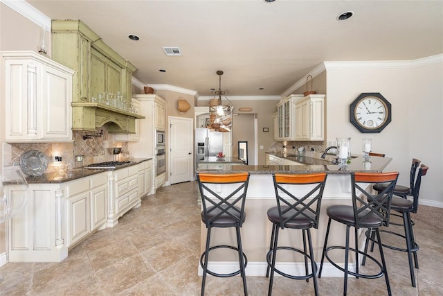 kitchen featuring a kitchen breakfast bar, backsplash, dark stone counters, pendant lighting, and appliances with stainless steel finishes