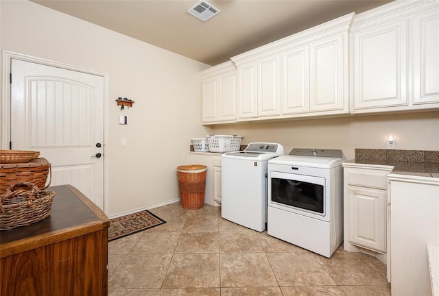 laundry room featuring cabinets, light tile patterned floors, and washing machine and dryer