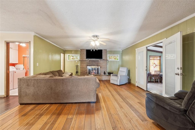 living room with ceiling fan, light hardwood / wood-style floors, a textured ceiling, and independent washer and dryer