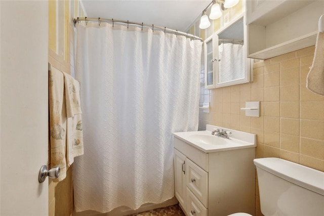 bathroom with vanity, decorative backsplash, toilet, tile walls, and walk in shower