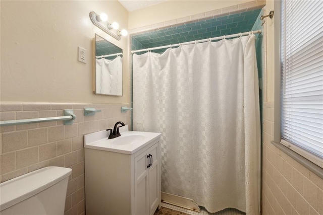 bathroom featuring vanity, curtained shower, toilet, and tile walls