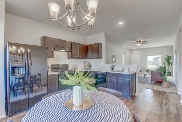 kitchen with ceiling fan with notable chandelier, sink, black appliances, wood-type flooring, and decorative light fixtures