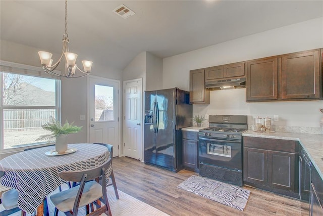 kitchen featuring dark brown cabinetry, black appliances, pendant lighting, a notable chandelier, and light hardwood / wood-style floors