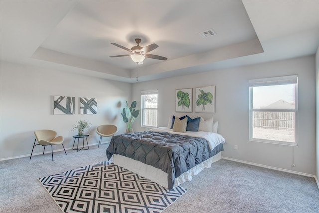 carpeted bedroom featuring a raised ceiling and ceiling fan