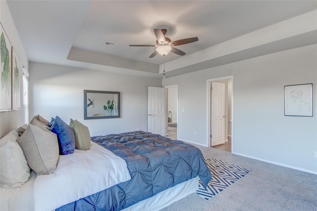 bedroom featuring a raised ceiling, ceiling fan, carpet, and ensuite bathroom