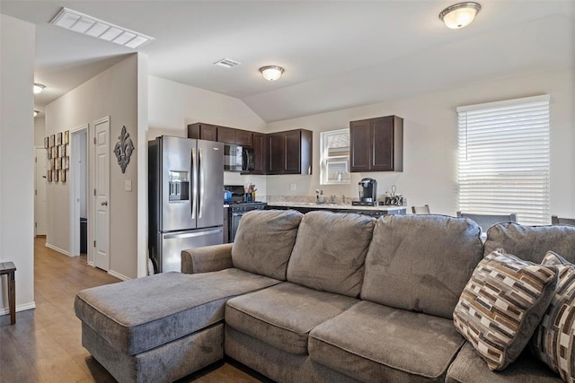 living room featuring light hardwood / wood-style floors, vaulted ceiling, and sink