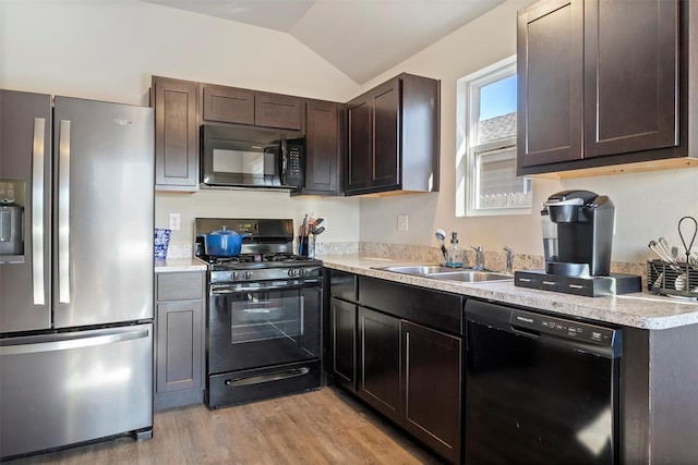 kitchen featuring dark brown cabinetry, sink, vaulted ceiling, black appliances, and light wood-type flooring