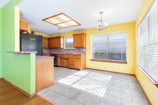 kitchen featuring dishwasher, decorative light fixtures, light tile patterned floors, fridge, and a notable chandelier