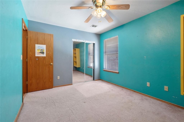 unfurnished bedroom featuring ceiling fan, a closet, and light carpet