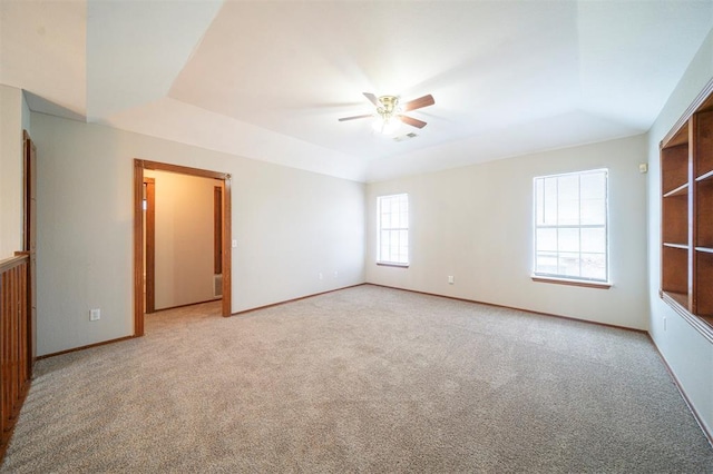 carpeted empty room with a tray ceiling and ceiling fan