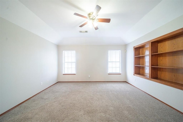 carpeted empty room featuring built in shelves, a wealth of natural light, and ceiling fan