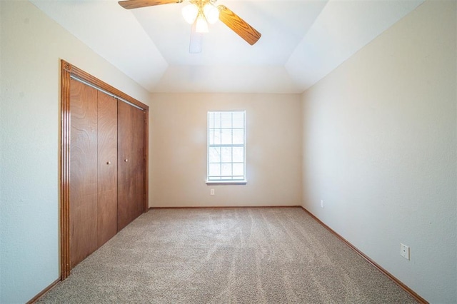 unfurnished bedroom with carpet flooring, ceiling fan, a closet, and vaulted ceiling