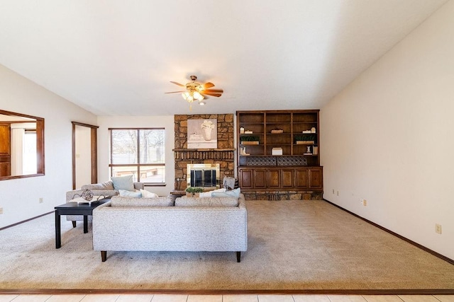 living room with built in shelves, light colored carpet, a stone fireplace, and ceiling fan