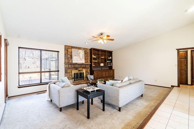 living room featuring light tile patterned floors, a stone fireplace, and ceiling fan