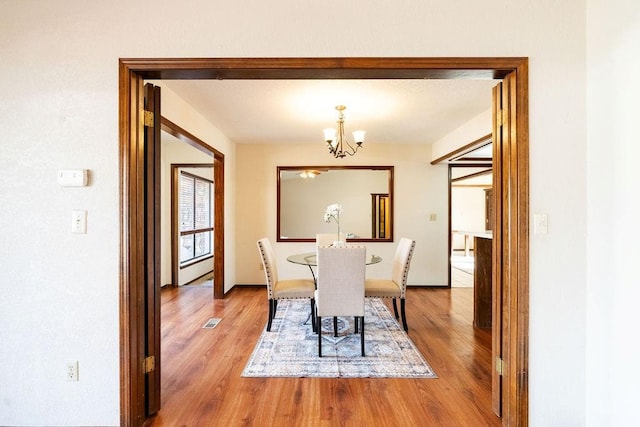 dining area featuring wood-type flooring, a baseboard radiator, and a chandelier