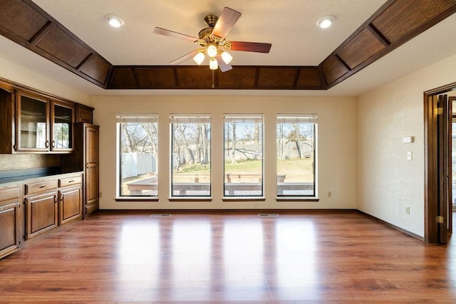 interior space featuring hardwood / wood-style flooring, a raised ceiling, ceiling fan, and plenty of natural light