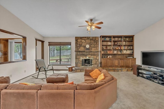 carpeted living room with a fireplace, vaulted ceiling, ceiling fan, and a healthy amount of sunlight
