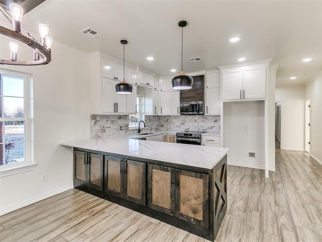 kitchen featuring white cabinetry, pendant lighting, decorative backsplash, appliances with stainless steel finishes, and ornamental molding