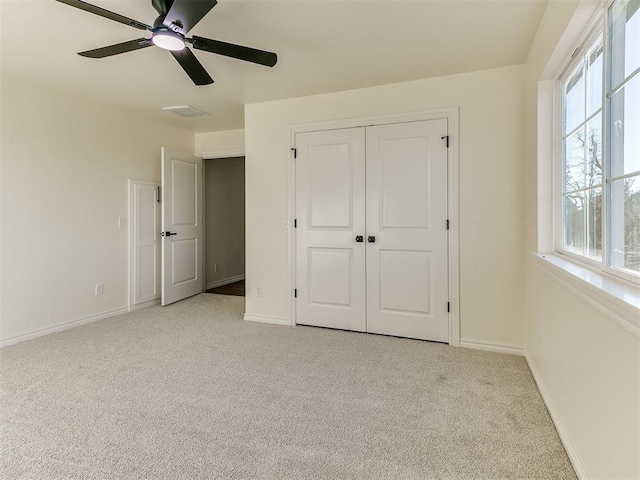 unfurnished bedroom featuring ceiling fan, a closet, and light carpet