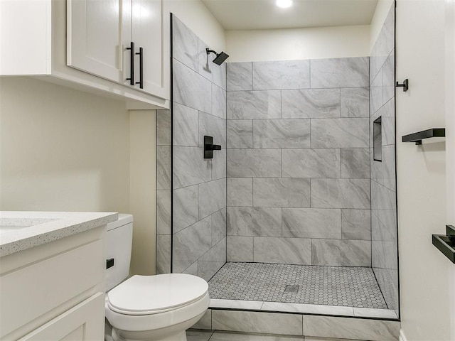 bathroom featuring vanity, toilet, and tiled shower