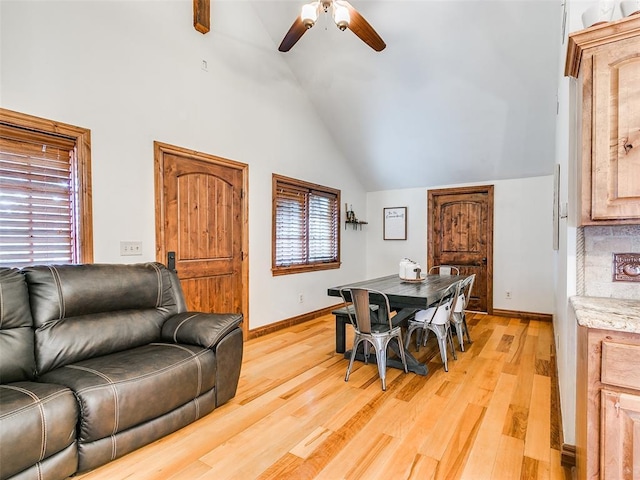 dining area with ceiling fan, high vaulted ceiling, and light hardwood / wood-style flooring