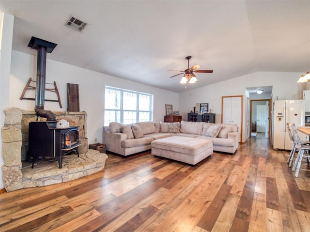 living room with hardwood / wood-style flooring, a wood stove, ceiling fan, and lofted ceiling