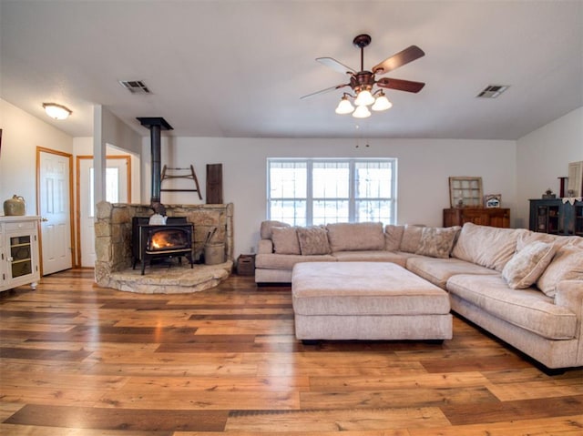 living room with hardwood / wood-style flooring, a wood stove, and ceiling fan