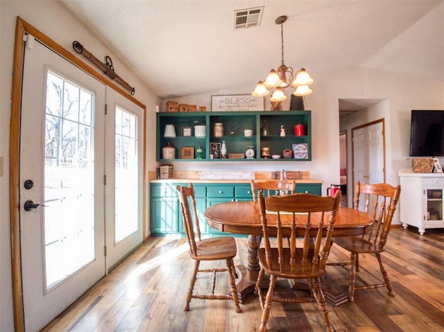 dining room featuring hardwood / wood-style floors, lofted ceiling, and a chandelier