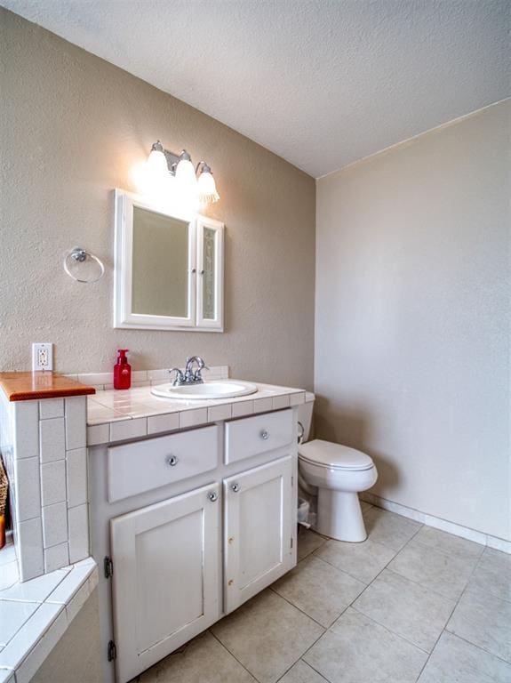 bathroom featuring tile patterned floors, vanity, a textured ceiling, and toilet